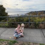 A little girl sits with her dog with the Puget Sound in the background